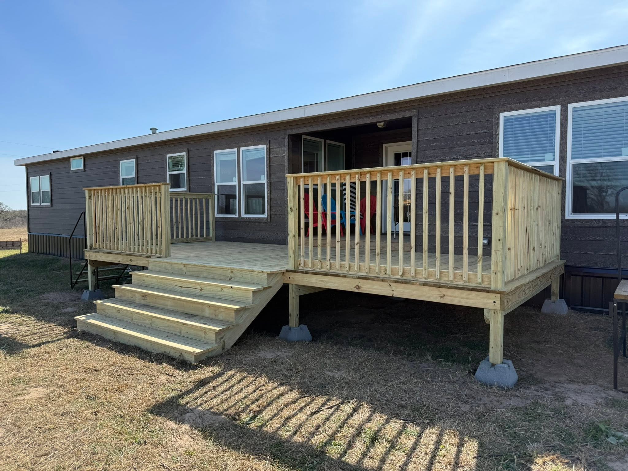 Large wraparound wood deck with railings and stairs