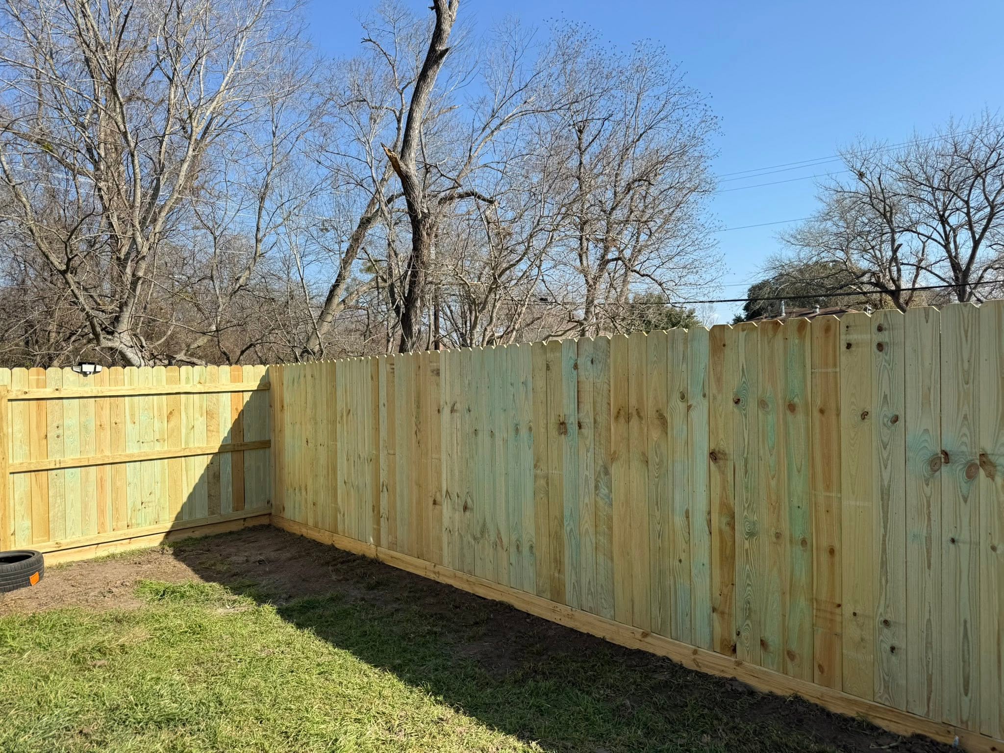 Capped wood privacy fence wrapping a corner of the yard
